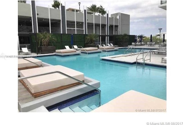 community pool with a patio area and fence