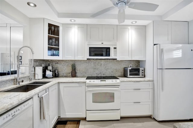 kitchen with light stone counters, a toaster, backsplash, a sink, and white appliances