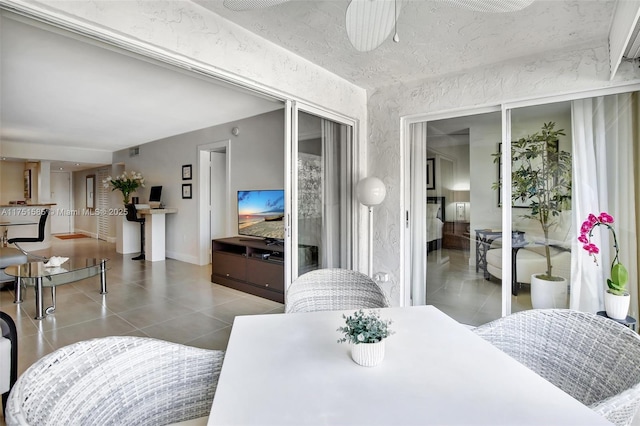 tiled dining space with a ceiling fan and baseboards