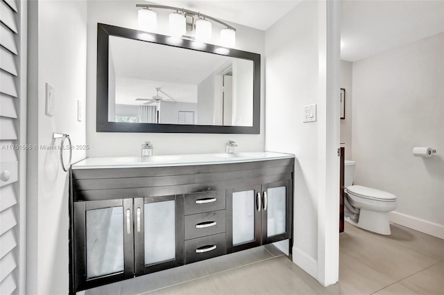 bathroom featuring double vanity, a sink, toilet, and baseboards