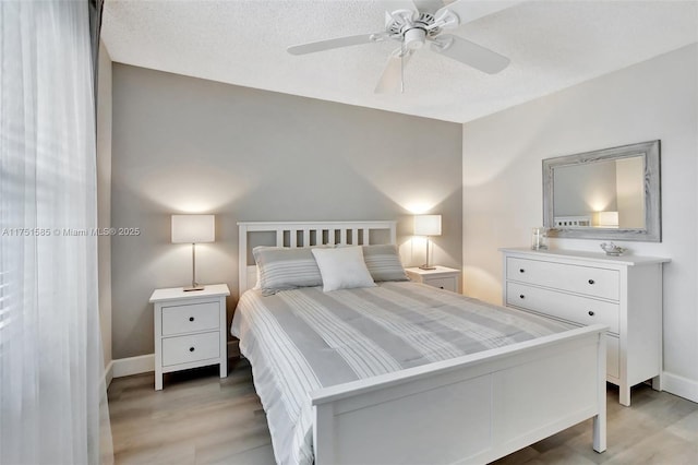 bedroom featuring a textured ceiling, light wood-style flooring, and baseboards