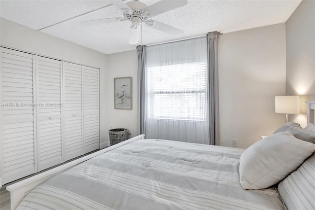 bedroom with a closet, a ceiling fan, and a textured ceiling