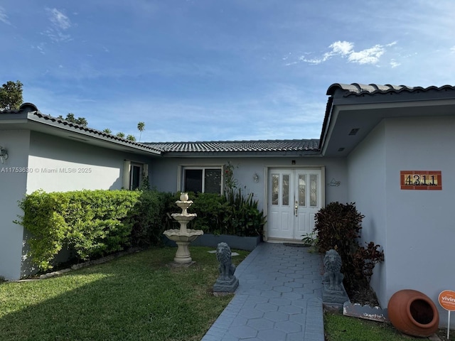 doorway to property with a lawn and stucco siding