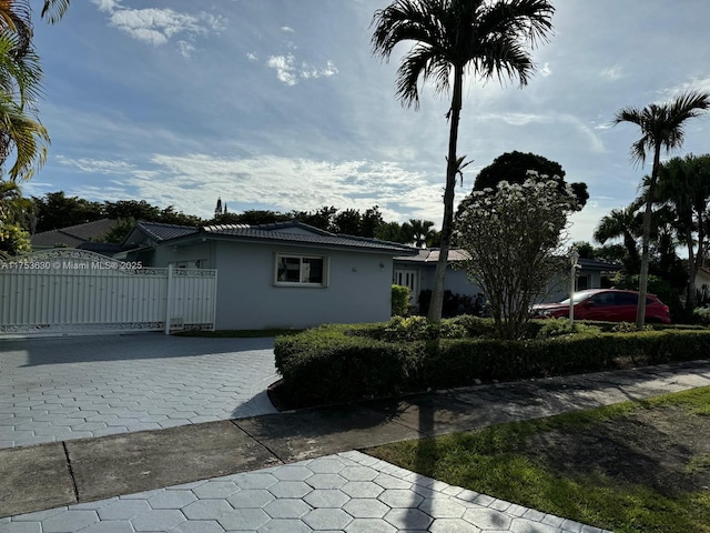 view of home's exterior with a gate, fence, metal roof, and stucco siding