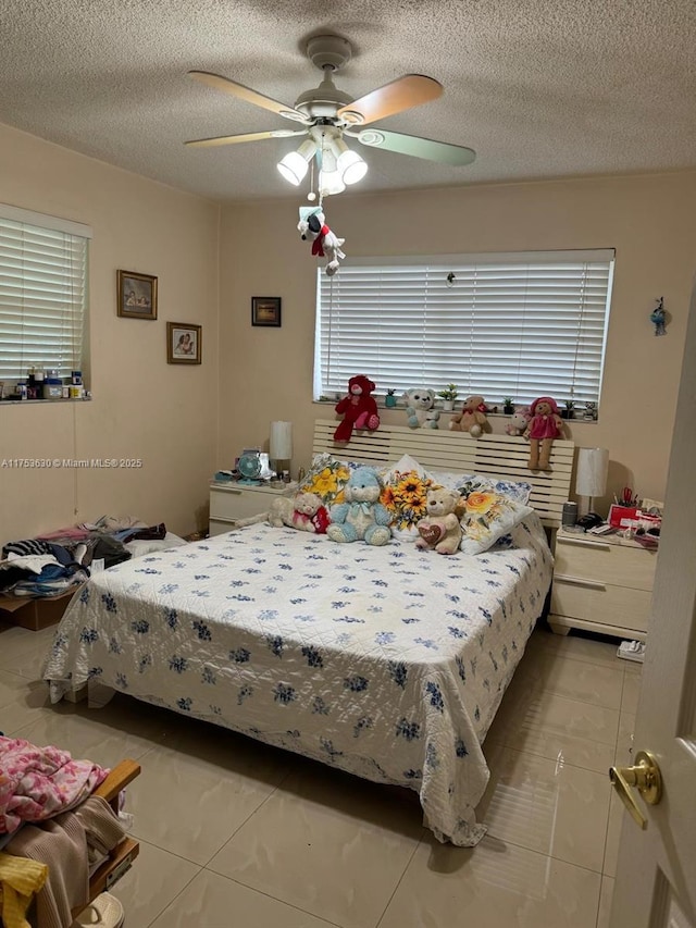 tiled bedroom featuring a ceiling fan and a textured ceiling