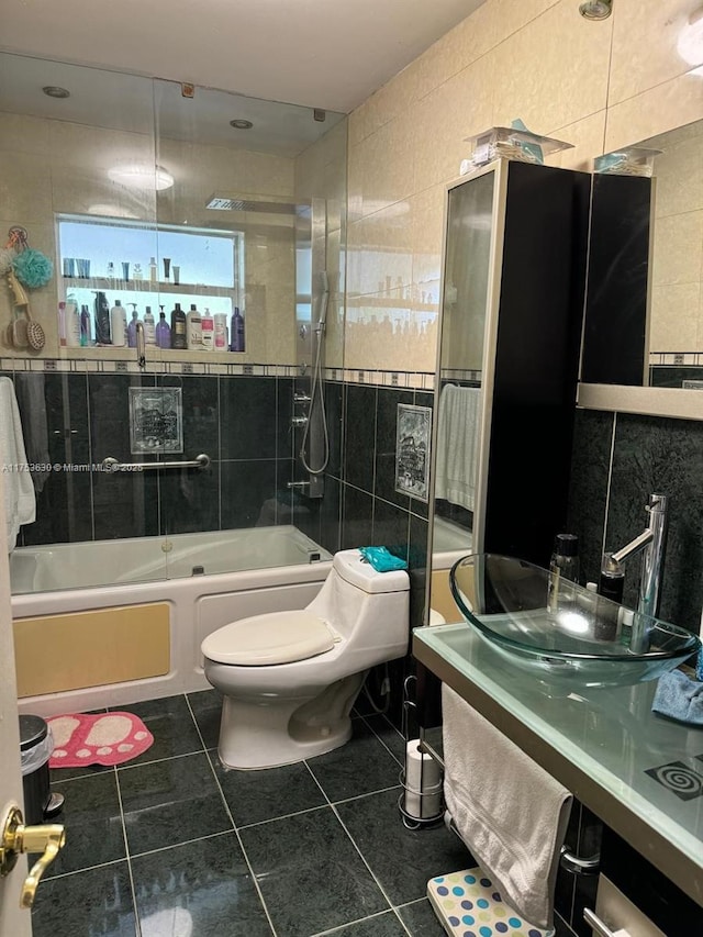 full bathroom with tile walls, toilet,  shower combination, tile patterned flooring, and a sink