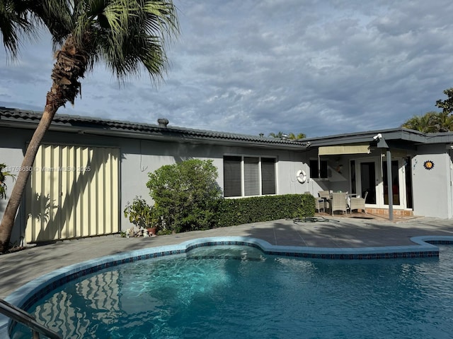 back of property with an outdoor pool, a patio, and stucco siding