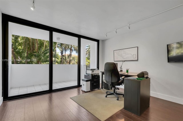 office area featuring rail lighting, floor to ceiling windows, baseboards, and wood finished floors