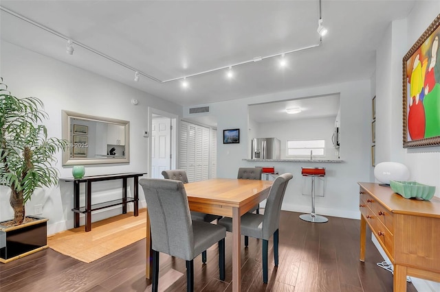 dining area featuring baseboards, hardwood / wood-style floors, visible vents, and track lighting