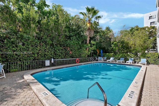 pool with a patio area and fence