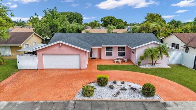 ranch-style house featuring driveway, a shingled roof, a gate, a front lawn, and stucco siding