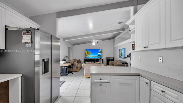 kitchen featuring stainless steel refrigerator with ice dispenser, light tile patterned floors, lofted ceiling with beams, white cabinets, and a peninsula