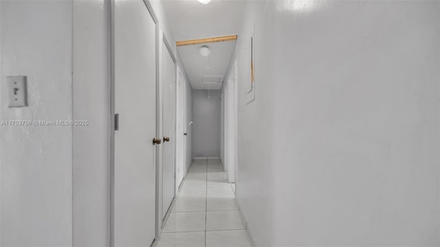 hallway featuring attic access and light tile patterned floors