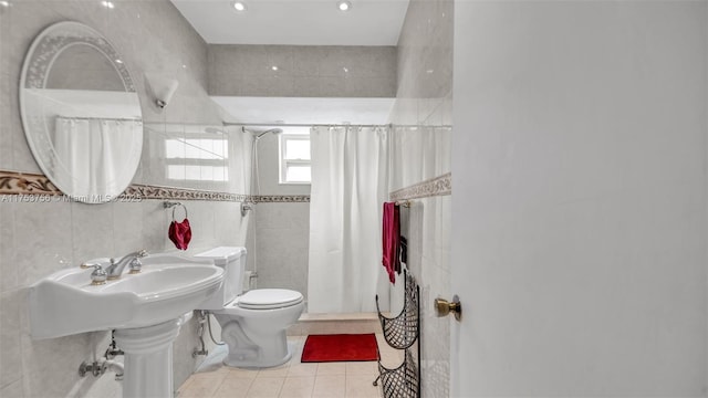 full bathroom with tiled shower, tile patterned flooring, toilet, and tile walls