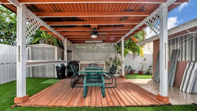 view of patio featuring a storage shed, ceiling fan, fence, outdoor dining area, and an outdoor structure