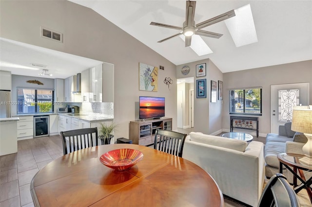 dining room featuring a skylight, beverage cooler, visible vents, baseboards, and ceiling fan