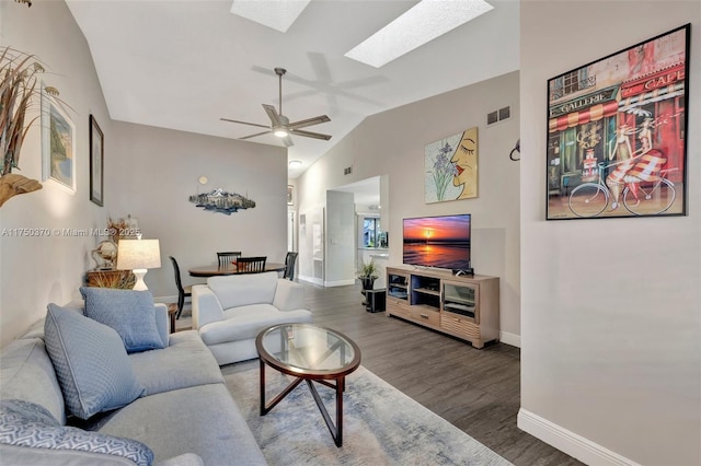 living area featuring ceiling fan, wood finished floors, visible vents, baseboards, and lofted ceiling with skylight