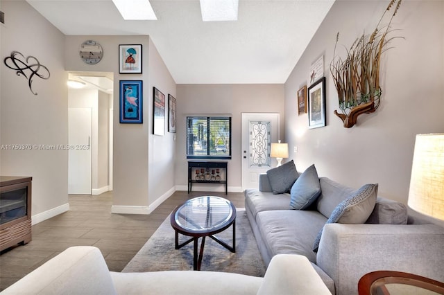 living room featuring lofted ceiling with skylight, baseboards, and wood finished floors