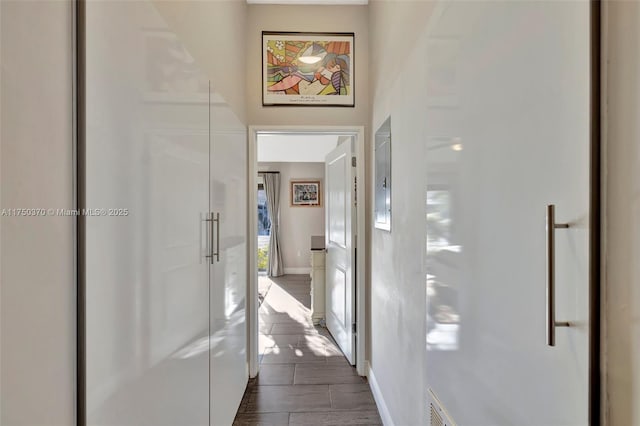 hallway with wood tiled floor, visible vents, and baseboards