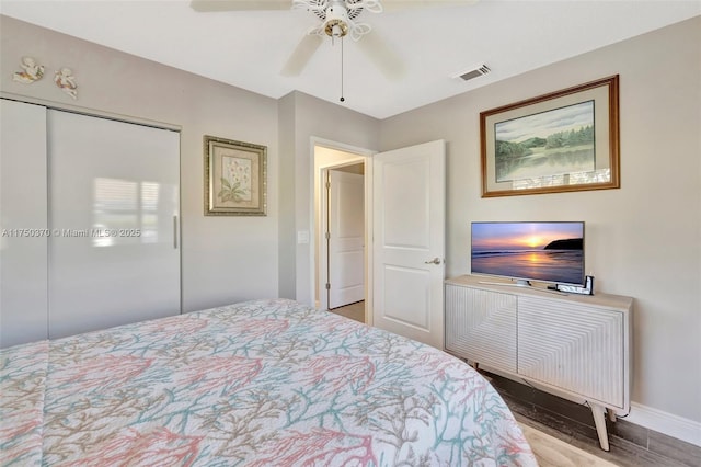 bedroom featuring baseboards, visible vents, ceiling fan, wood finished floors, and a closet