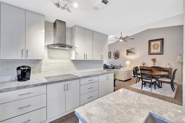 kitchen featuring light wood finished floors, visible vents, decorative backsplash, wall chimney exhaust hood, and black electric stovetop