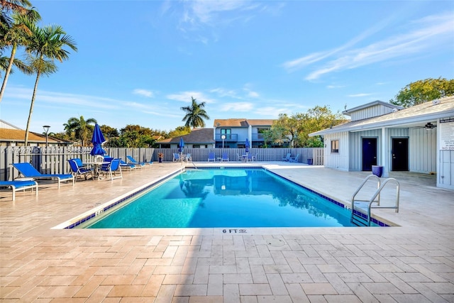 community pool with a patio area and fence