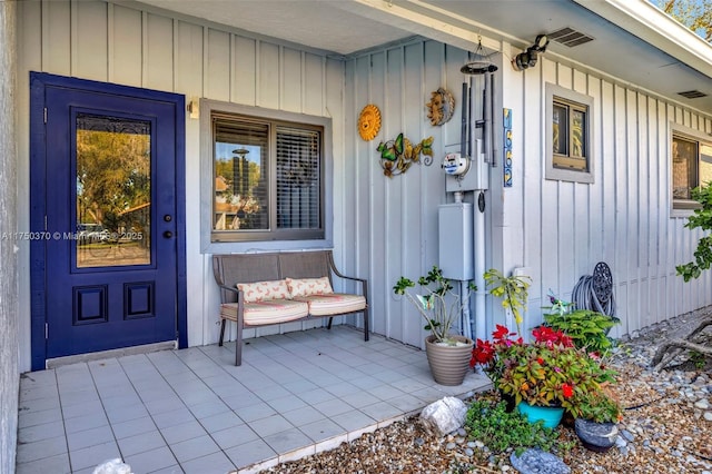 property entrance with board and batten siding, visible vents, and a porch