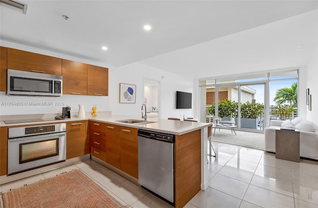 kitchen featuring open floor plan, a peninsula, light countertops, stainless steel appliances, and a sink