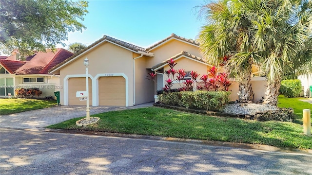 mediterranean / spanish-style home featuring decorative driveway, an attached garage, a front yard, and stucco siding