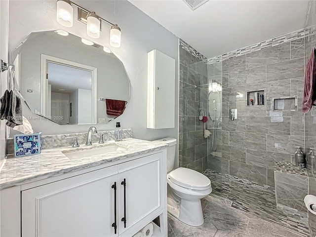 full bath with toilet, visible vents, a tile shower, and vanity