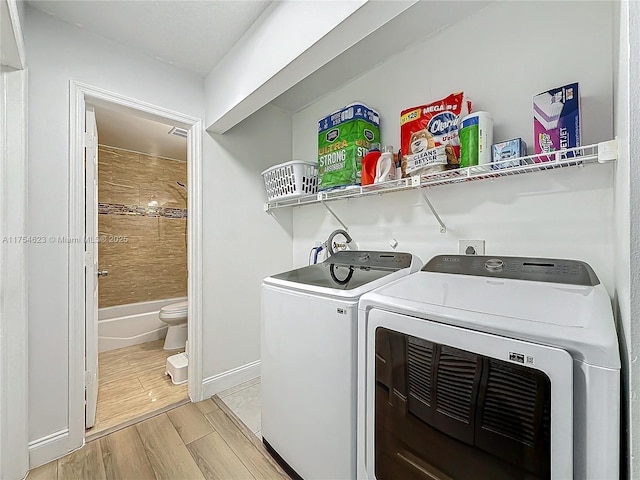 laundry area featuring washer and dryer, wood finish floors, laundry area, and baseboards