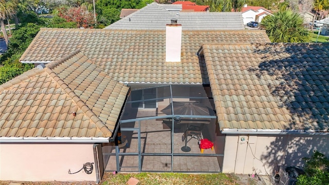 exterior space featuring a tile roof, a chimney, and stucco siding