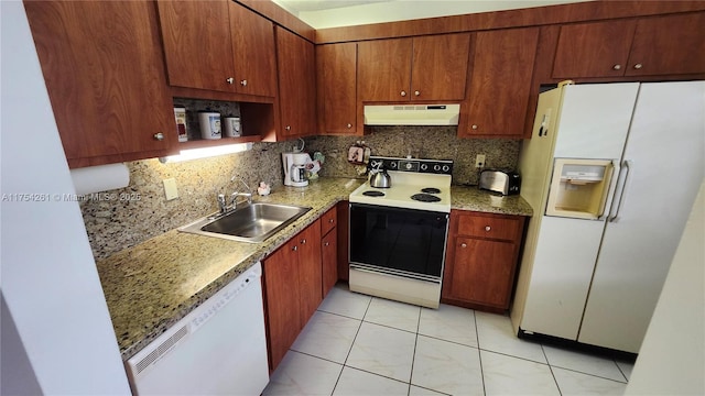 kitchen featuring white appliances, decorative backsplash, light countertops, under cabinet range hood, and a sink