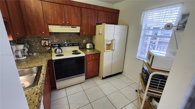 kitchen with white appliances, a sink, under cabinet range hood, and backsplash