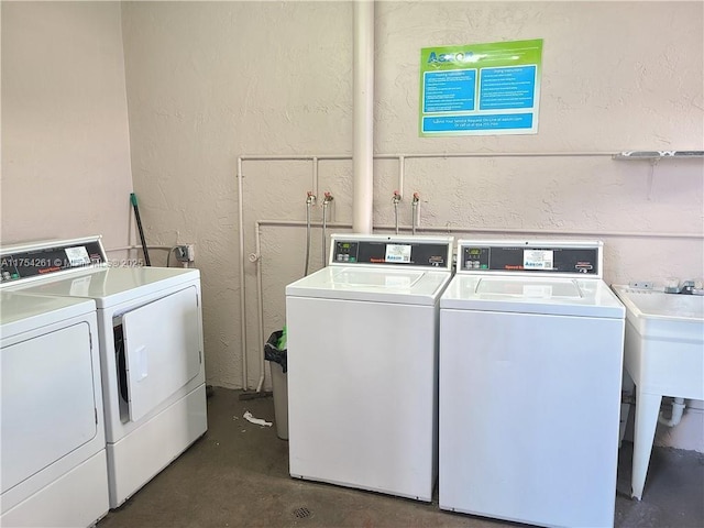 shared laundry area featuring a sink, a textured wall, and washing machine and clothes dryer