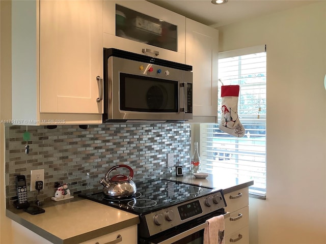 kitchen featuring stainless steel appliances, light countertops, backsplash, and white cabinetry