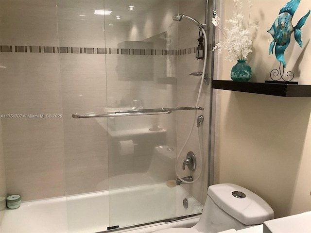 bathroom featuring toilet and combined bath / shower with glass door