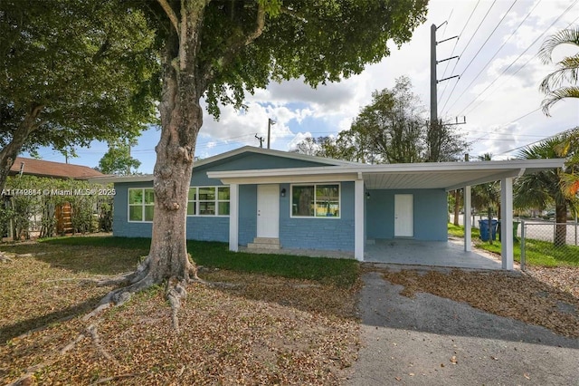 single story home with an attached carport, concrete block siding, and fence