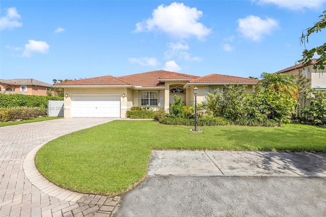 mediterranean / spanish home featuring decorative driveway, stucco siding, a front yard, a garage, and a tiled roof