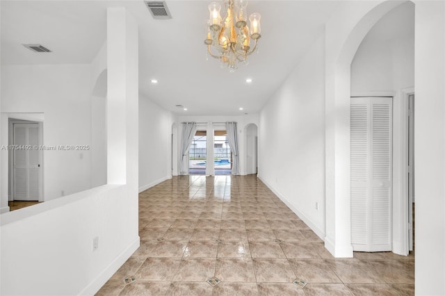 corridor featuring arched walkways, tile patterned flooring, visible vents, and baseboards