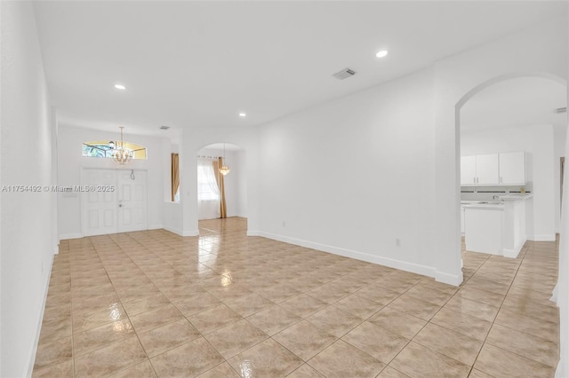 unfurnished living room with arched walkways, a notable chandelier, recessed lighting, visible vents, and baseboards