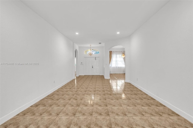 interior space featuring arched walkways, light tile patterned floors, recessed lighting, and baseboards