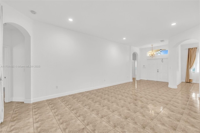 unfurnished living room with recessed lighting, arched walkways, and baseboards