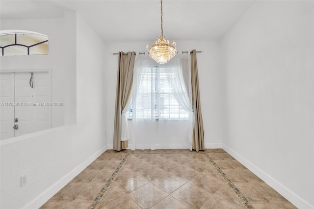 spare room with a notable chandelier and baseboards