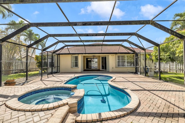 view of swimming pool featuring a patio area, fence, a pool with connected hot tub, and a lanai