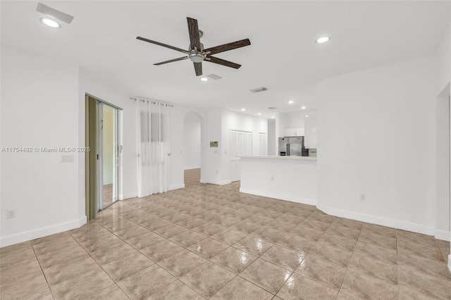 unfurnished living room featuring arched walkways, recessed lighting, visible vents, a ceiling fan, and baseboards