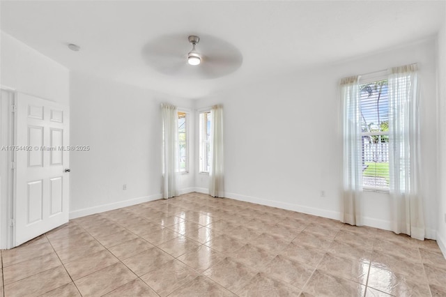 unfurnished room featuring a ceiling fan, a wealth of natural light, and baseboards