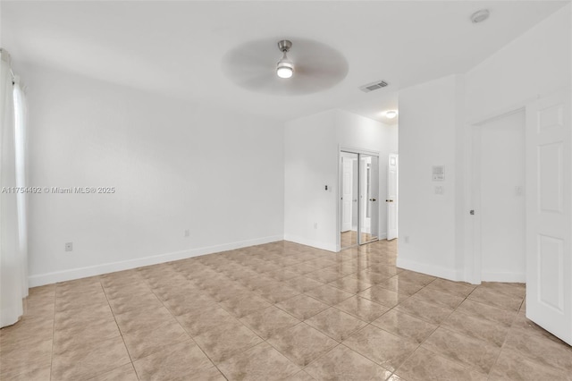 empty room featuring a ceiling fan, visible vents, baseboards, and light tile patterned flooring