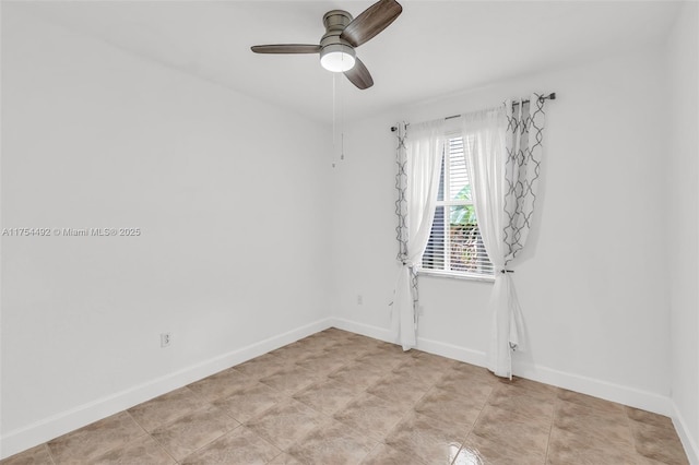 spare room with a ceiling fan and baseboards