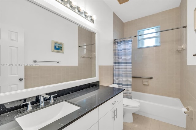 bathroom featuring toilet, shower / tub combo with curtain, tile patterned floors, vanity, and tile walls